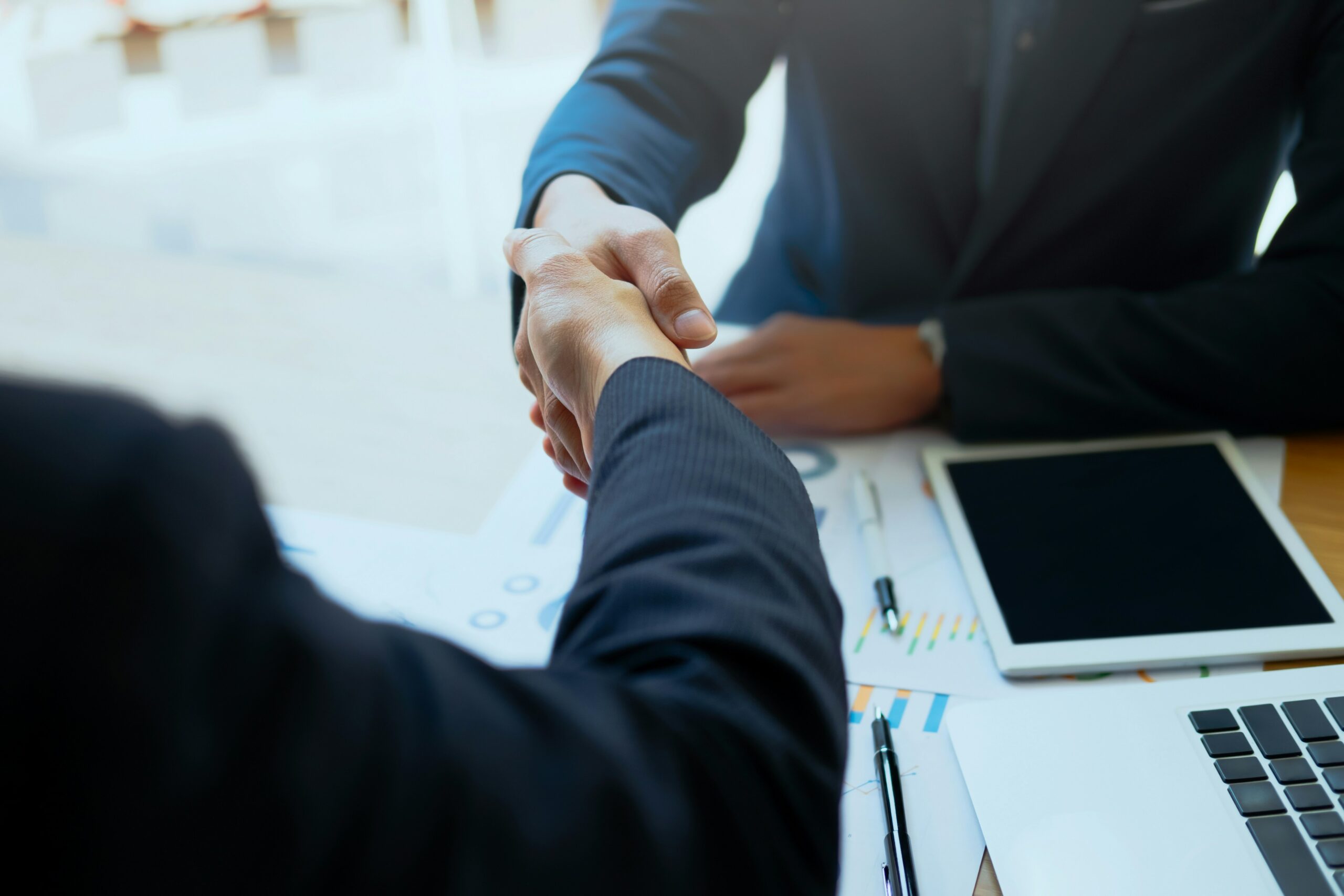 Two people shaking hands over desk