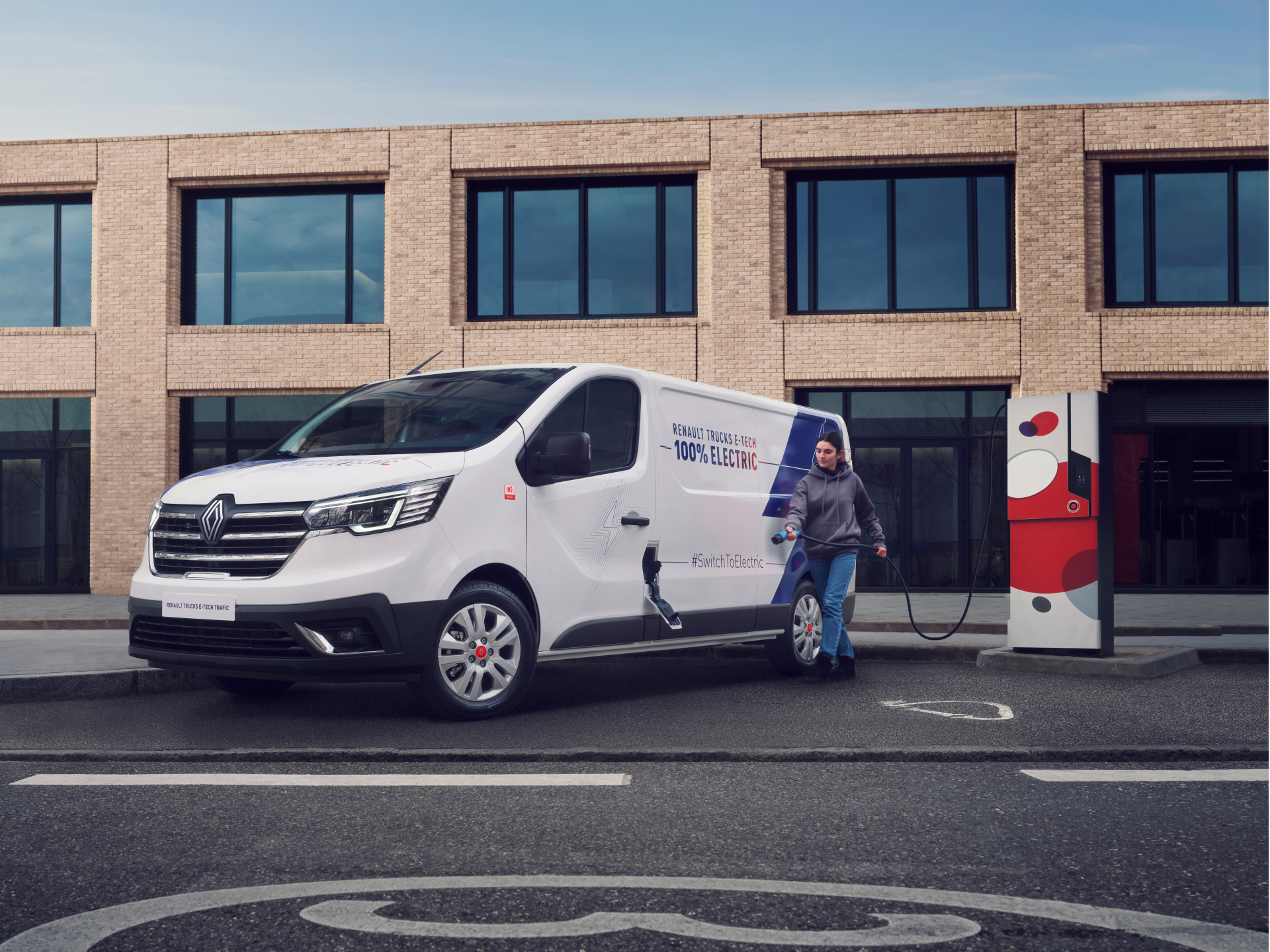 Renault Trafic E-Tech van parked on street with person holding charging cable