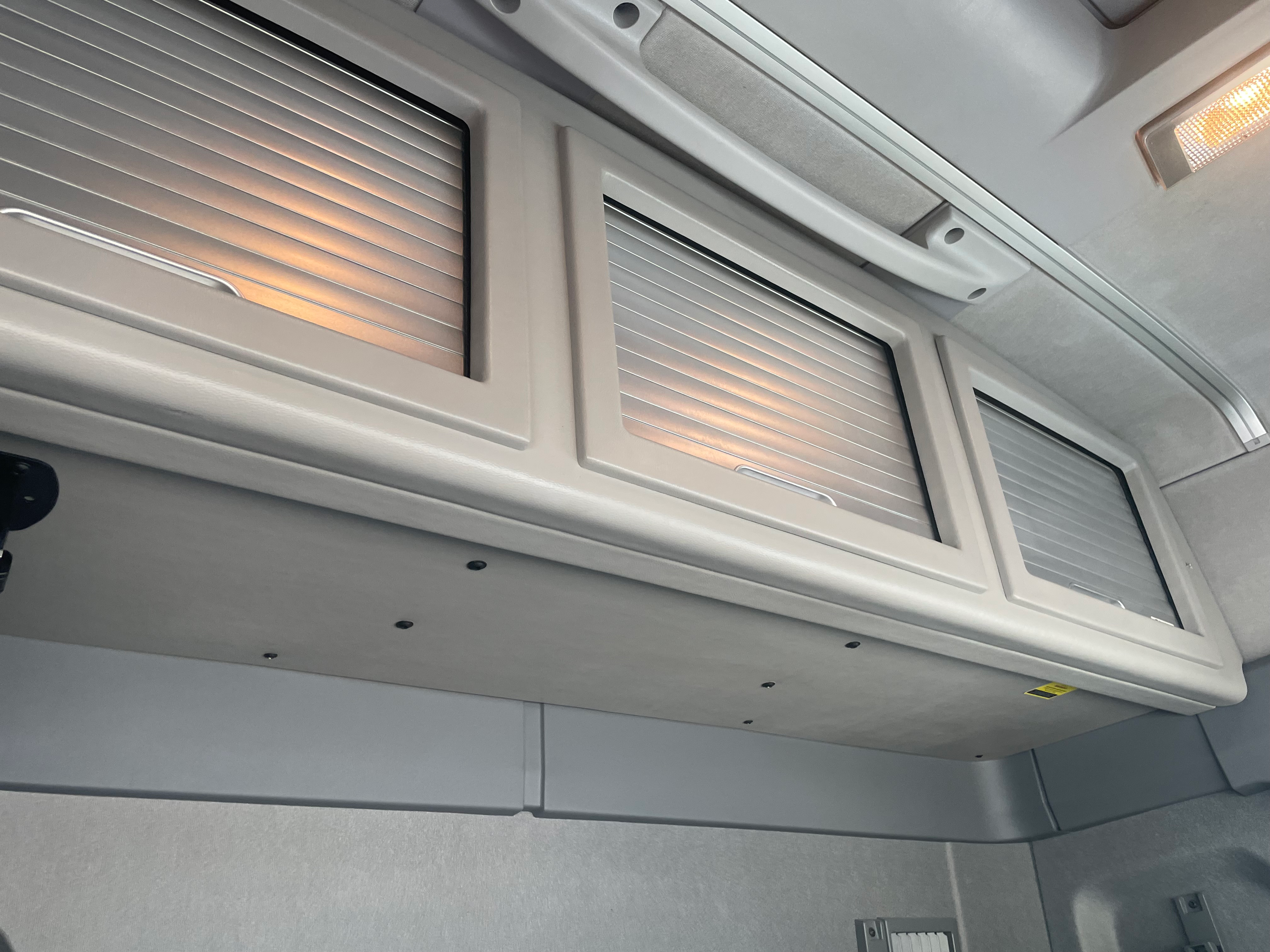 Overhead storage compartments with roller doors inside Renault Trucks T 6x2 Euro 6 cab, ideal for long-haul driver storage.